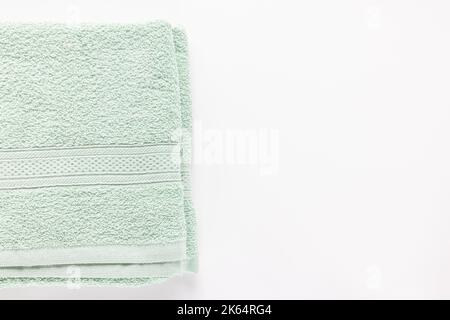 Nouveau drap de bain plié vert menthe ou serviettes sur fond blanc. Vue de dessus, espace de copie Banque D'Images