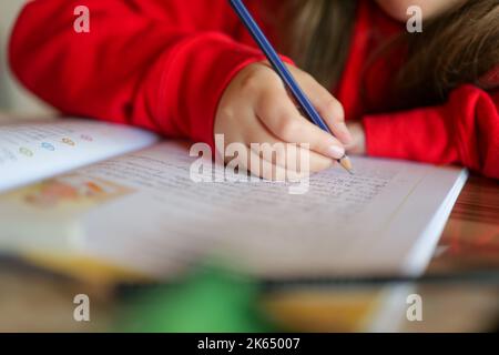 Devoirs.Etudier et éducation.Schoolgirl fait son devoir.crayon dans une main d'enfant écrit des mots dans un bloc-notes Banque D'Images