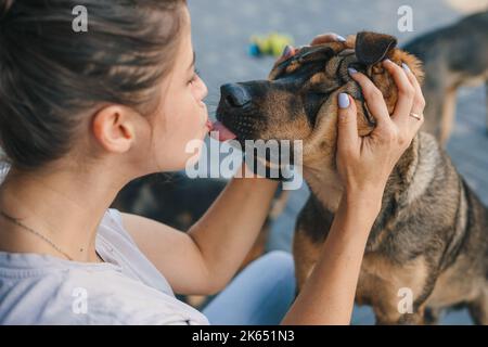 Belle jeune femme petant son chien et lui donnant un baiser à la maison, à l'extérieur. Bonne famille à l'extérieur. Style de vie extérieur. Famille amusante. Banque D'Images