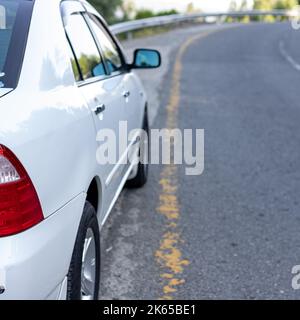 Voiture blanche avec feux arrière stationnés sur le côté d'une route asphaltée dans la zone de montagne Banque D'Images