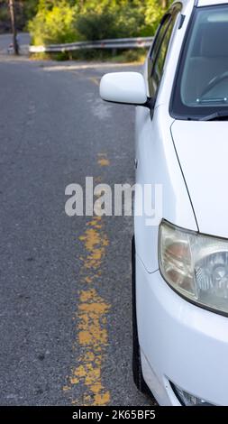 Une voiture blanche garée sur le côté d'une route asphaltée Banque D'Images