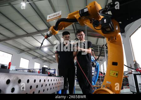 BINZHOU, CHINE - 12 OCTOBRE 2022 - des techniciens testent un robot industriel d'ustensiles de cuisine récemment développé dans une société de recherche scientifique à Binzhou, Shand Banque D'Images