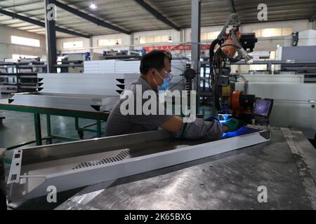 BINZHOU, CHINE - 12 OCTOBRE 2022 - Un travailleur utilise des appareils intelligents pour produire des ustensiles de cuisine dans un atelier d'une entreprise de fabrication d'ustensiles de cuisine à Banque D'Images