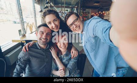 Point de vue prise de photos d'amis gaies prenant le selfie dans la pizzeria posant et souriant, riant et faisant des gestes ensemble. Amitié et jeunes heureux concept. Banque D'Images
