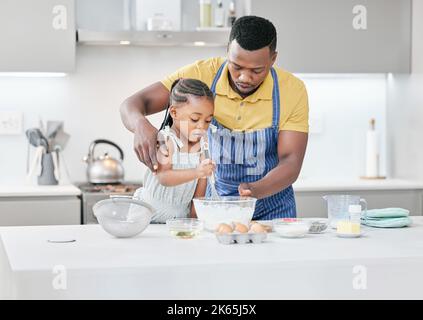 Ne le battez pas si vite. Un beau jeune père qui se joint à sa fille et l'aide à cuire dans la cuisine à la maison. Banque D'Images