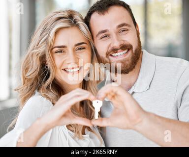 Portrait d'un nouveau couple caucasien en forme de coeur avec les mains et en tenant les clés de la maison pour se déplacer dans un nouvel appartement. Déménagement après avoir acheté le produit en premier Banque D'Images
