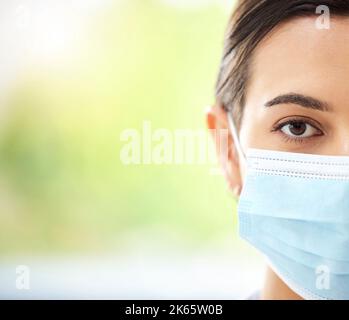 Portrait d'une femme hispanique portant un masque et regardant sérieusement dans un bureau d'hôpital Banque D'Images