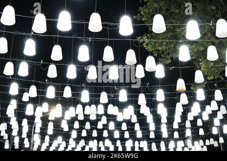 Une guirlande avec beaucoup de lanternes décoratives est accrochée sur une rue de nuit, ville décoration de rue Banque D'Images