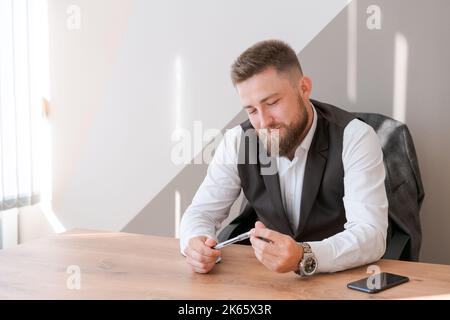 Portrait barbu homme d'affaires assis au bureau méditant tenant le stylo dans ses mains et considérant un concept d'affaires pour l'avenir. Banque D'Images