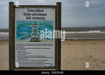 Un panneau d'avertissement sur une plage déserte par mauvais temps indique un danger pour les nageurs Banque D'Images