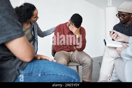 Homme ayant une panne pendant la séance de thérapie de groupe au sujet de la dépendance. Conseiller donnant un soutien à l'homme africain pleurant déprimé au groupe psychologique Banque D'Images