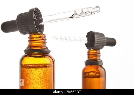 Deux pipettes avec sérum sont sur des cols de flacons ouverts bruns. Banque D'Images