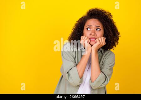 Photo de triste ondulée femme millénaire look vide espace porter chemise grise isolée sur fond jaune Banque D'Images