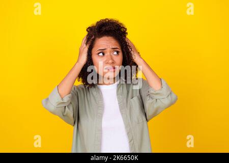 Photo de stress maud millenny femme mains cheveux look vide espace porter chemise grise isolée sur fond jaune couleur Banque D'Images