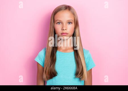 Gros plan photo de jeune fille petit mignon préadolescence écolière porter cyan t-shirt cheveux blond look sérieux photo cadre isolé sur couleur rose vif Banque D'Images