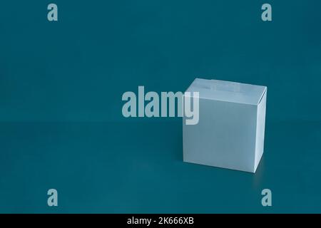 Une boîte en carton vierge carrée bleue sur un arrière-plan de studio bleu coloré avec espace de copie. Concept de cadeau, de livraison et d'expédition. Banque D'Images