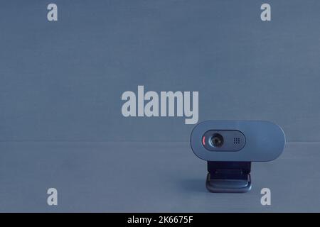 Une webcam sans fil isolée se trouve sur son support avec le voyant rouge prêt à enregistrer sur un arrière-plan studio bleu avec un espace de copie. Sécurité, technol Banque D'Images