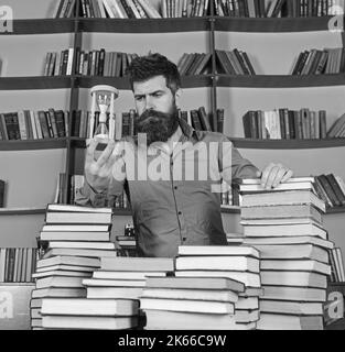Concept de bibliothécaire. Professeur, scientifique avec la barbe se tient à table avec des livres, défoqué. L'homme sur le visage réfléchi se tient entre des piles de livres, tandis que Banque D'Images
