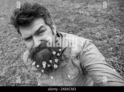 La taille basse sur le visage en clin d'œil repose sur l'herbe, défochée. Homme avec la barbe aime le printemps, vert prairie fond. Type avec des fleurs de celandine moins en barbe Banque D'Images