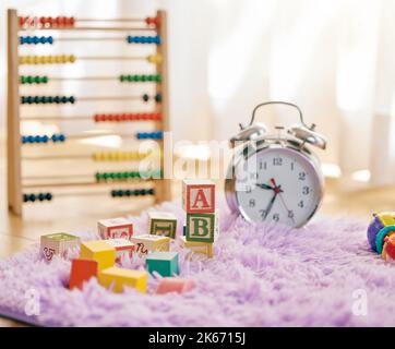 Son temps d'apprentissage. Photo de la vie d'une horloge et de plusieurs jouets sur un tapis moelleux. Banque D'Images