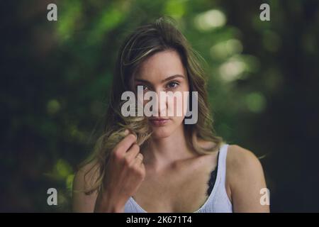 Belle jeune femme joyeuse avec fond vert foncé moody dans la nature Banque D'Images