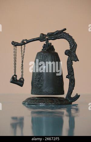 Une ancienne cloche en bronze sur le stand de dragon avec gong et un fond rose. Banque D'Images