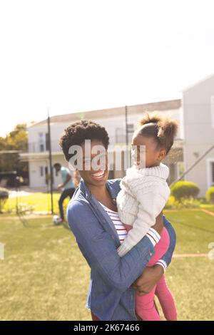 Bonne mère et fille afro-américaine passant du temps ensemble et jouant au football à l'extérieur Banque D'Images
