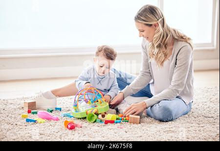 Je pense que j'ai créé un génie. Une maman assise avec son fils pendant qu'il joue avec ses jouets. Banque D'Images