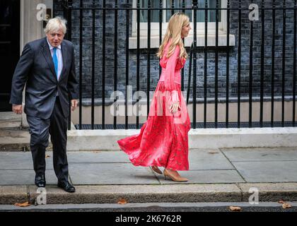 Boris Johnson, député, alors Premier ministre, et Carrie Johnson, sa femme, en robe rouge fuchsia Haumr, marchent dans des directions opposées avant son adieu spee Banque D'Images