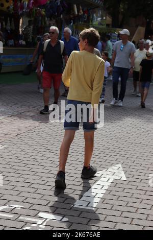 Junge 14 Jahre im Sommer kurze Hose symbolisch mit Pfeil entwicklung Vorwärts pubertät erwachsen werden / Boy 14 ans on a Street short jeans Banque D'Images