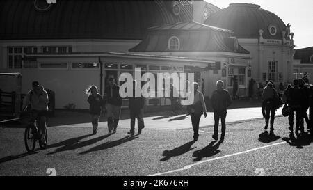 Les gens marchent en fin d'après-midi sous le soleil sur le front de mer de Worthing à côté de la jetée, West Sussex, Royaume-Uni. Banque D'Images