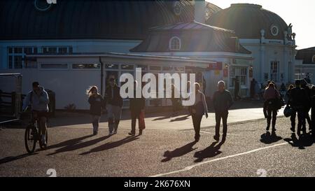 Les gens marchent en fin d'après-midi sous le soleil sur le front de mer de Worthing à côté de la jetée, West Sussex, Royaume-Uni. Banque D'Images