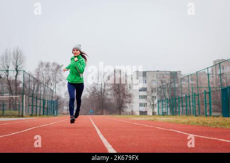 Jeune athlète de course sur le terrain de sport en automne. Portrait du corps entier. Un mode de vie actif et sain. Espace Banque D'Images