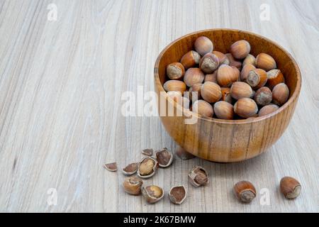 Noisettes dans un bol avec peu de craquelures à côté sur la table. Banque D'Images