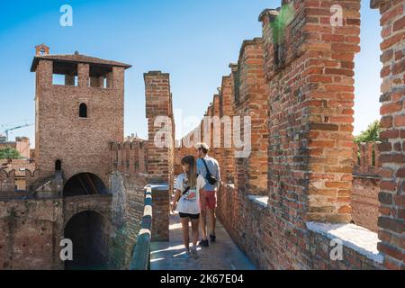 Les jeunes voyagent, vue arrière en été d'un couple touristique explorant les murs de la forteresse de Castelvecchio à Vérone, Italie Banque D'Images