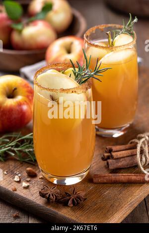 Cocktail de cidre de pomme avec des tranches de pommes et des pommes fraîches au romarin en arrière-plan, Banque D'Images