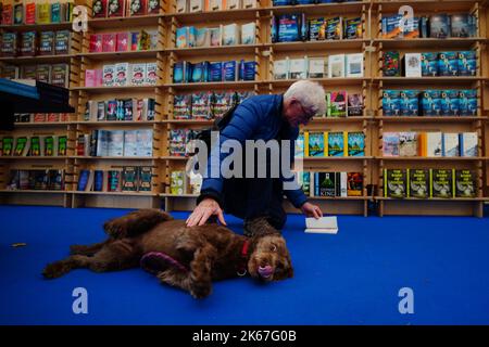 Un homme perse un livre avec son chien au Cheltenham Literature Festival. Date de la photo: Mercredi 12 octobre 2022. Banque D'Images