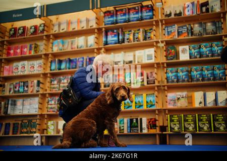 Un homme perse un livre avec son chien au Cheltenham Literature Festival. Date de la photo: Mercredi 12 octobre 2022. Banque D'Images