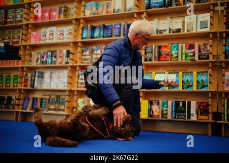 Un homme perse un livre avec son chien au Cheltenham Literature Festival. Date de la photo: Mercredi 12 octobre 2022. Banque D'Images