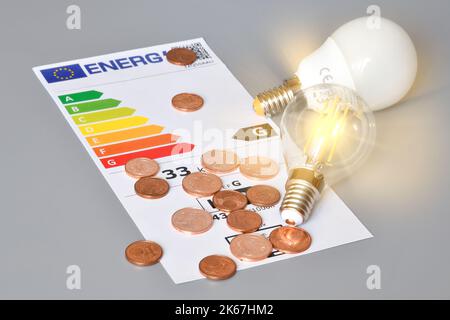 Tableau d'évaluation de l'efficacité énergétique avec ampoules lumineuses et centimes d'euro sur fond gris, gros plan. Concept d'augmentation du prix de l'énergie. Banque D'Images