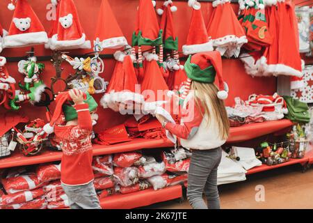 Les enfants choisissent un chapeau du père noël dans le magasin Banque D'Images