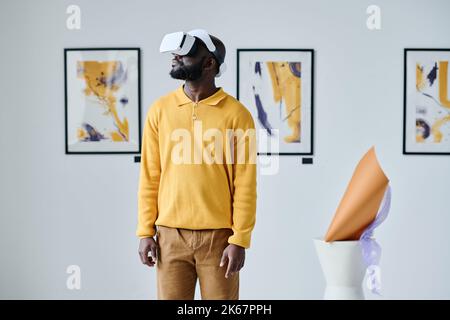 Jeune homme africain utilisant des lunettes VR lors d'une visite de la galerie d'art Banque D'Images