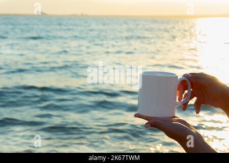 maquette de tasse. mug blanc par sublimation mockup tenant par une fille dans un paysage marin. gobelet de sublimation blanche pour le vendeur de tasse et le designer pour e-commerce à la vente en ligne Banque D'Images