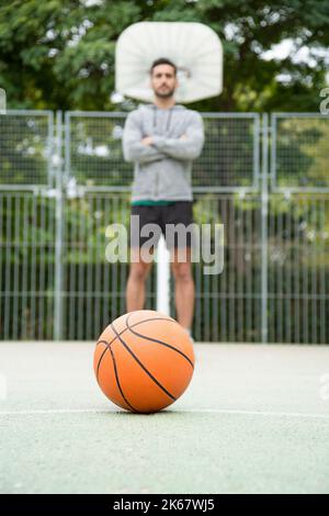 Concentrez-vous sur un ballon de basket-ball sur un terrain en plein air avec un joueur de basket-ball Banque D'Images