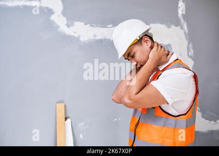 Un jeune ouvrier asiatique de la construction tient son cou dans la douleur de blessures de travail Banque D'Images