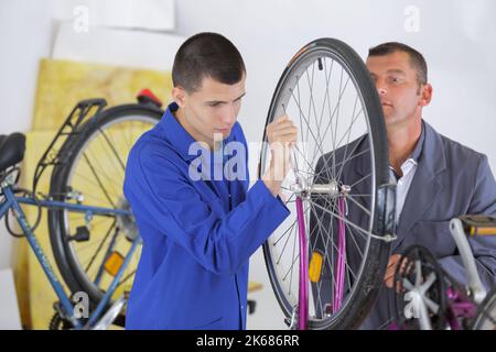 mécanicien stagiaire travaillant sur un vélo sous supervision Banque D'Images