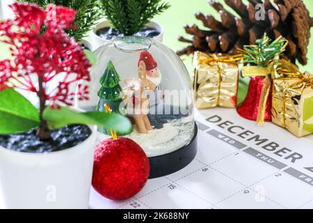 Concept de Noël coloré, boule à neige festive et autres décorations sur le calendrier de décembre, pins, cône de pin, cadeaux, cloche et boule, joyeux Chris Banque D'Images