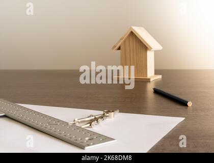 Objets sur la table dans un bureau d'architecte avec une petite maison en bois à l'arrière-plan pour la décoration. Banque D'Images