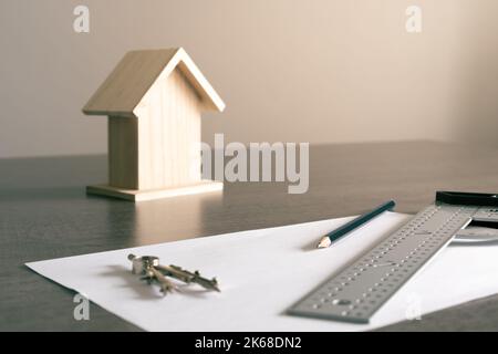 Objets sur la table dans un bureau d'architecte avec une petite maison en bois à l'arrière-plan pour la décoration. Banque D'Images