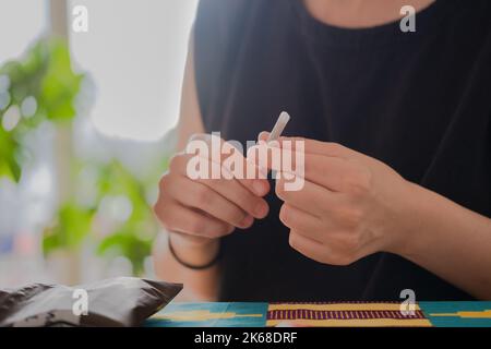 Personne méconnaissable qui fait une cigarette de tabac à la maison Banque D'Images